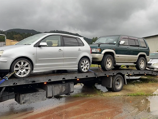Tow truck transporting two scrap cars in Tauranga